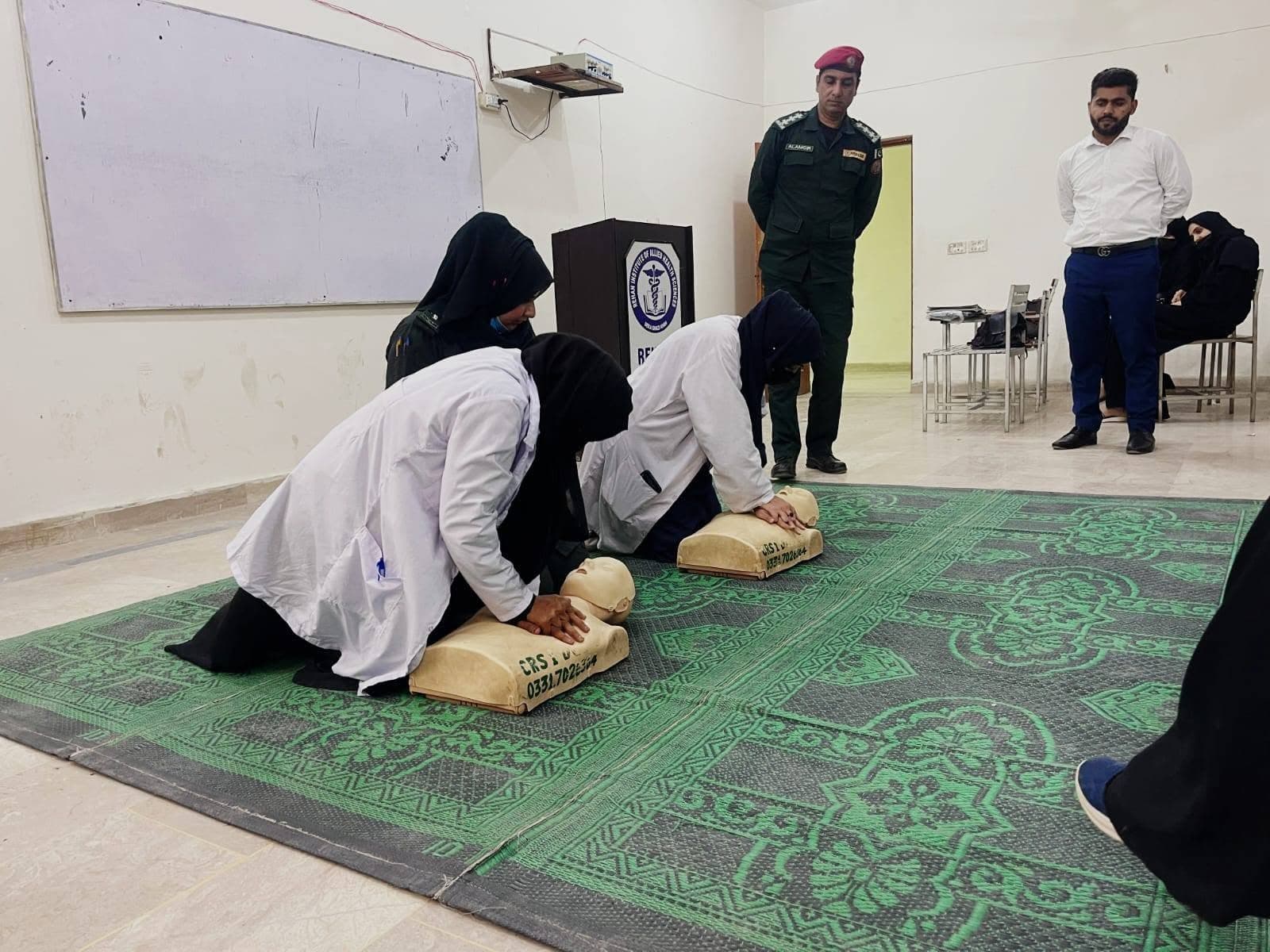 Nursing students practising CPR on training manikins while instructors watch